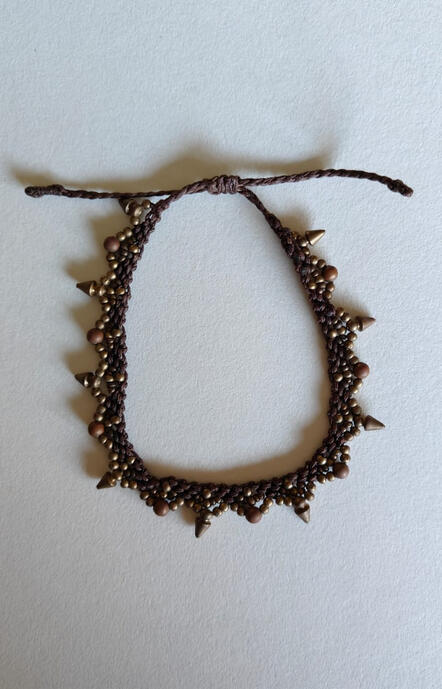 Step into the rich heritage of Indian craftsmanship with this stunning handwoven anklet. Meticulously crafted by skilled artisans, this piece features durable, dark brown waxed thread intricately woven to create a tribal-inspired silhouette. Adorned with