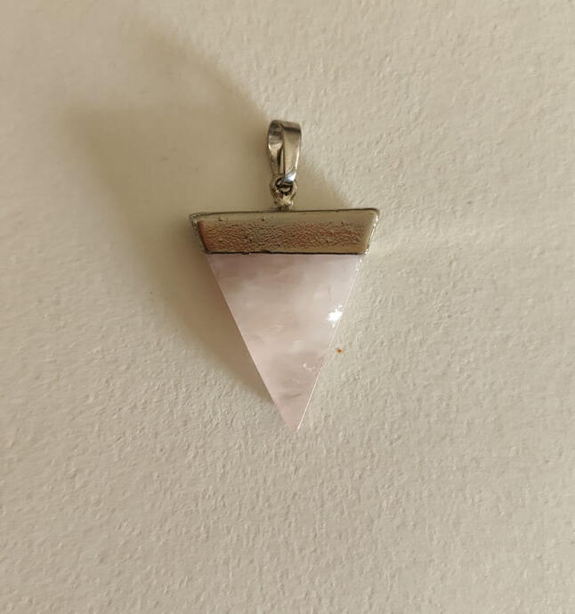 Where gentle meets geometric. This minimalist triangle pendant features a soft pink rose quartz crystal, symbolizing love and calm, set in a sleek antique silver bezel. The clean lines and cool-toned metal create a modern, feminine piece that’s perfect fo